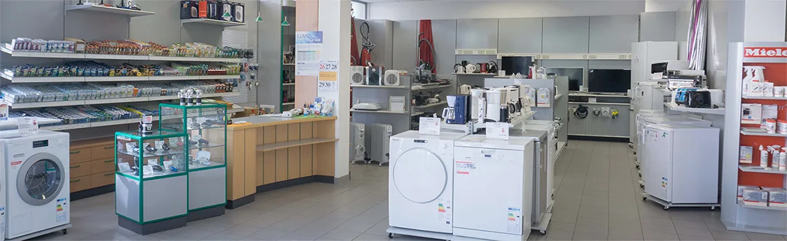Verkaufsraum mit Regalen voller Installationsmaterial, Vitrinen mit grünen Kanten und Waschmaschinen